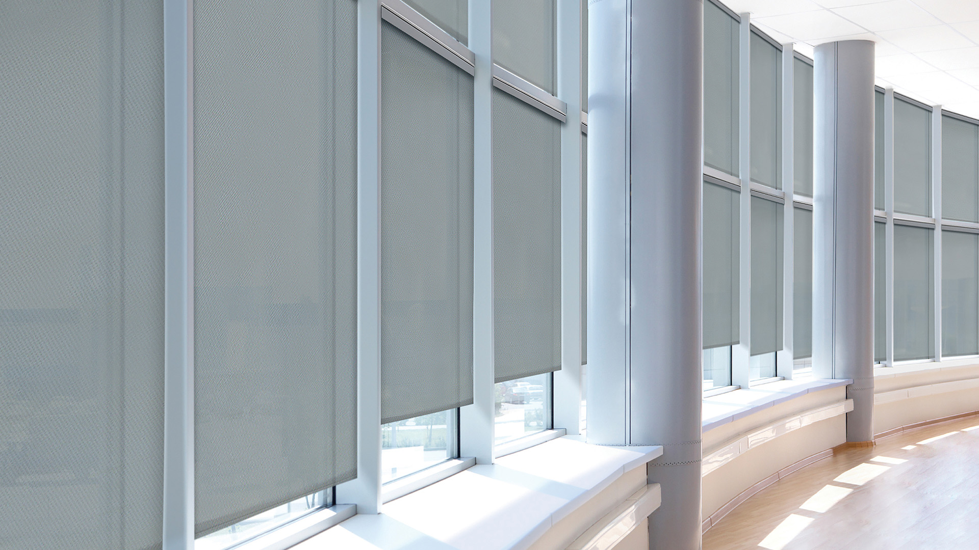 Tall windows in a vaulted-ceiling room with shades lowering.